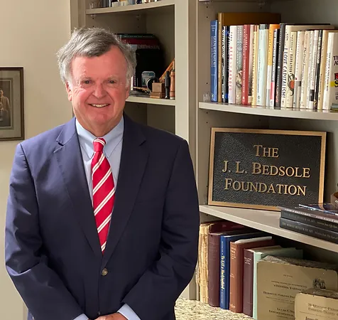 A man in suit and tie standing next to books.